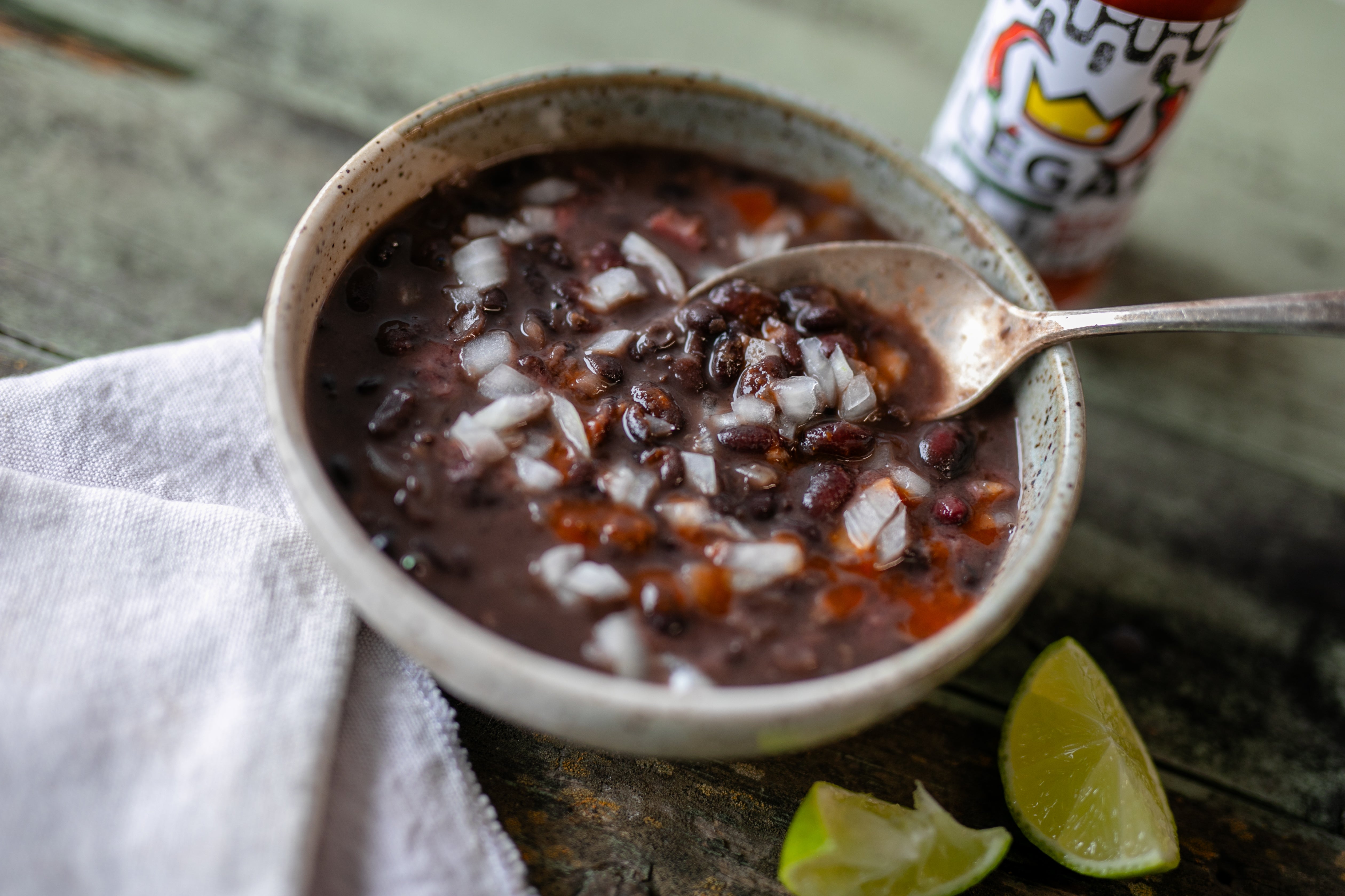 black bean soup in a serving bowl with onion and hot sauce
