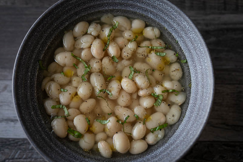 Cooked Caballero beans, sprinkled with black pepper, basil to garnish.