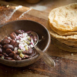 Cooked Ayocote Morado, topped with diced onion with a side of homemade tortillas-Rancho Gordo, Heirloom beans.