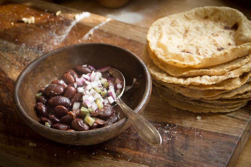 Cooked Ayocote Morado, topped with diced onion with a side of homemade tortillas-Rancho Gordo, Heirloom beans.