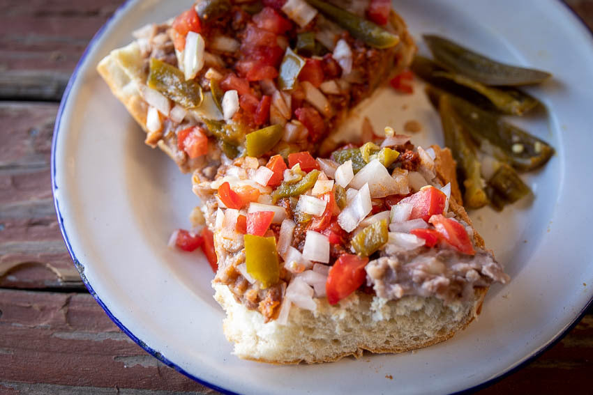 Two pieces of bread with refried beans and pickled jalapenos, salsa,