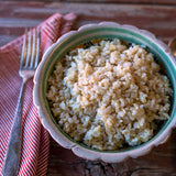 In a small bowl there's cooked California Brown Rice. In each side there's a silver fork and spoon.- Rancho Gordo