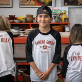 Three children wearing the Rancho Gordo Team Bean T-Shirt. Two of them are showing the back of the shirt. 