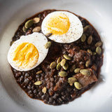 Cooked black caviar lentils topped with half cut boiled egg and seeds-Rancho Gordo