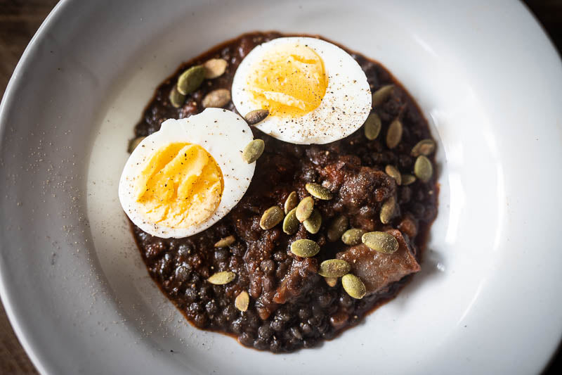 Cooked black caviar lentils topped with half cut boiled egg and seeds-Rancho Gordo