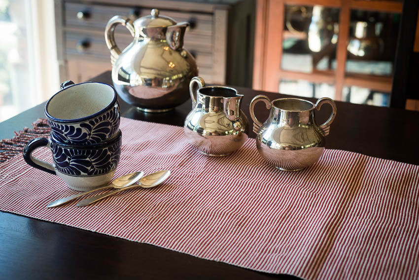 Natural Dye Table Runner display in a table with a silver tea set and cups with spoon. 