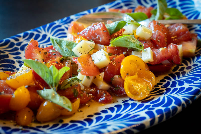 A tomato salad doused with Rancho Gordo banana vinegar with basil leaves an cheese. 