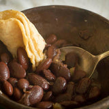 Bowl of cooked Ayocote Morado beans with a rolled up tortilla-Rancho Gordo, Heirloom beans.