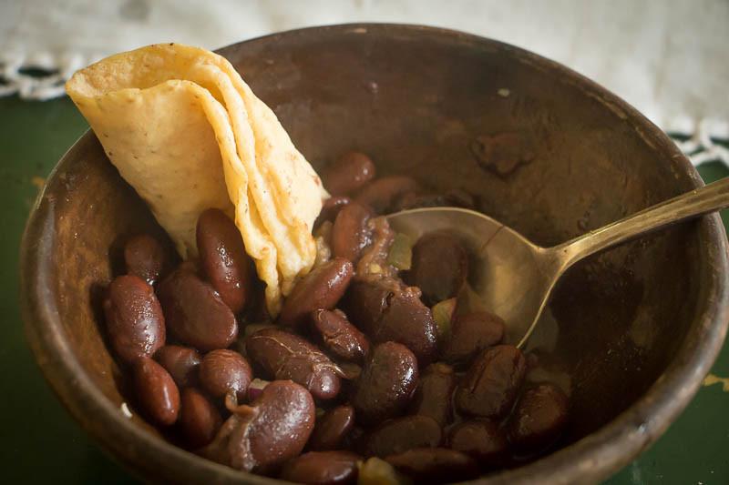 Bowl of cooked Ayocote Morado beans with a rolled up tortilla-Rancho Gordo, Heirloom beans.