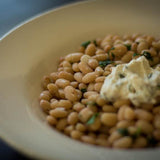 Cooked Alubia Blanca, topped with ricotta cheese and herbs-Rancho Gordo, Heirloom beans.